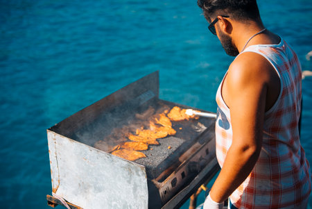 Enjoy a delightful summer BBQ by the beautiful ocean, grilling up some delicious fish todayの写真素材