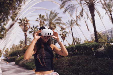 A young woman enjoys virtual reality in nature, embracing the excitement of the digital worldの写真素材