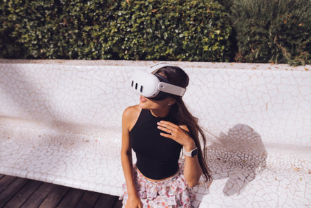 A Young Woman is Enthusiastically Enjoying a Virtual Reality Experience while Outdoors in Natureの写真素材