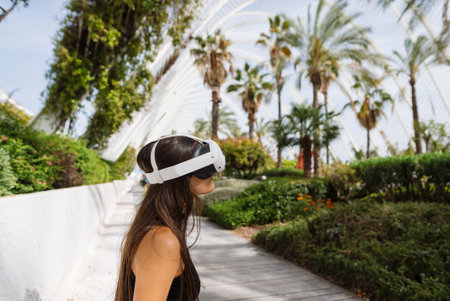 A woman in a VR headset explores a beautiful, lush outdoor environment with vibrant greenery