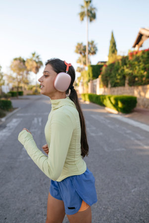 A Young Woman Jogging Outdoors while Wearing Headphones, Enjoying the Fresh Air and Musicの写真素材