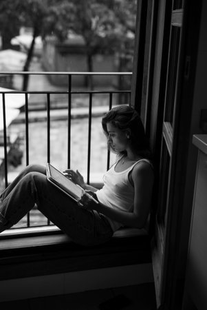 Enjoying Cozy Reading in a Relaxing and Serene Window Nook Filled with Comfort and Calmnessの写真素材