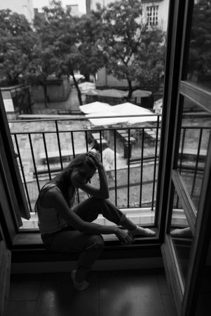 A Contemplative Moment by the Window in Striking Black and White Imagery and Toneの写真素材