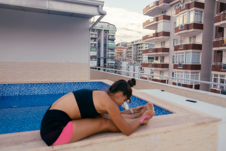 Engaging in Yoga Practice by the Poolside with a Modern Urban Backdrop for Inspirationの写真素材