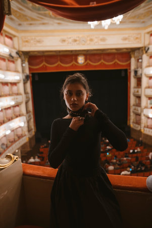 An Elegant Woman in a Stunning Black Dress Enjoying a Theater Performance Experience