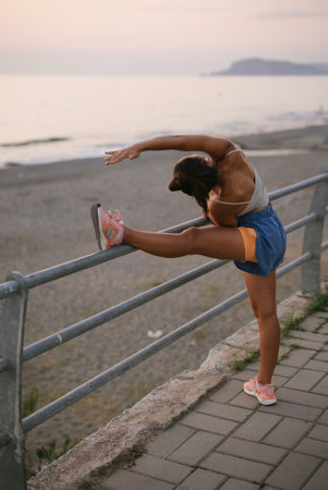 Engaging in Dynamic Fitness Stretching by the Beach during a Beautiful Sunset timeの写真素材