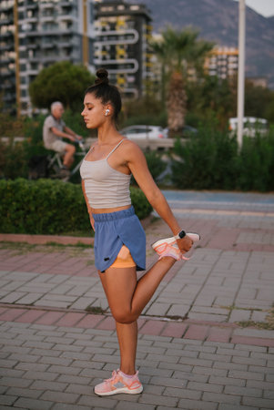 A Young Woman is Seen Stretching Outdoors in Comfortable Sportswear, Embracing Nature