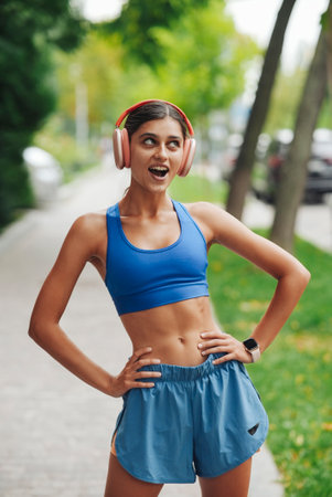 A Fit and Young Woman Enjoying Her Outdoor Workout While Listening to Music with Headphonesの写真素材