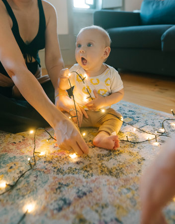 A Sweet Baby Joyfully Playing with Twinkling Christmas Lights in a Cozy Home Settingの写真素材