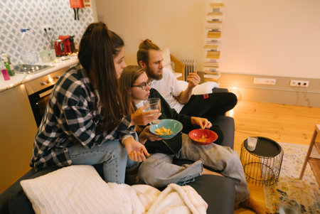 A group of friends relishing in a delightful movie night filled with tasty snacks at homeの写真素材