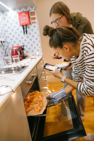 Two close friends joyfully baking together in a modern and stylish kitchen environmentの写真素材