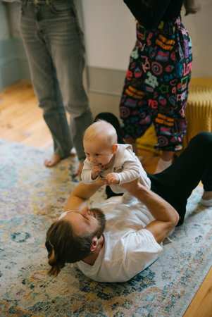 A Delightful and Playful Interaction Taking Place Between Adult and Baby on a Colorful Rugの写真素材