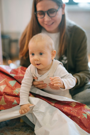 Joyful Moments A Baby and Parent Unwrap Holiday Gifts Together with a Happy Smileの写真素材