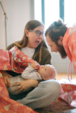 A Joyful Family Celebration where a Baby excitedly Opens Gifts with Loved Ones Aroundの写真素材