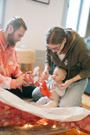 Joyful Family Moment Unwrapping Gifts Together with Their Cherished Baby this Holiday Seasonの写真素材