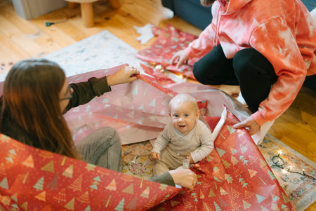 Experience the joyful moments of unwrapping colorful holiday gifts together with your babyの写真素材