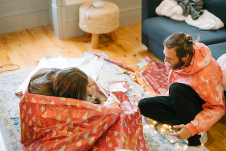 This is a candid moment capturing the holiday gift wrapping fun and joy of the seasonの写真素材