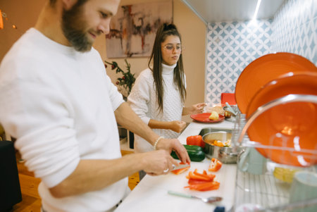 A couple happily cooking together in a modern kitchen filled with colorful ingredients and tools