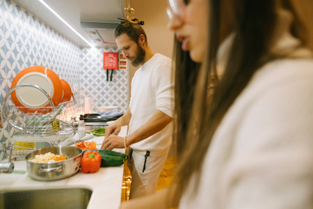 A Couple Joyfully Cooking Together in a Bright and Modern Kitchen Setting Right Nowの写真素材