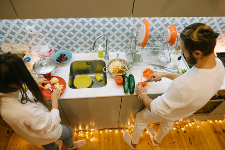 A happy couple is joyfully cooking together in their cozy and inviting kitchen spaceの写真素材