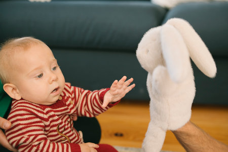 Adorable Baby Engaging Playfully with a Soft and Cuddly Bunny Toy While Smiling Joyfullyの写真素材