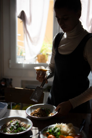 A woman is busily preparing a meal in her sunlit kitchen space