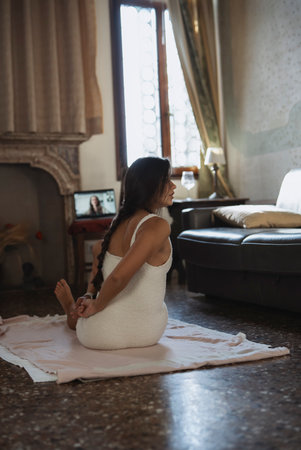 A woman is practicing yoga in a cozy and inviting indoor setting, surrounded by peaceの写真素材