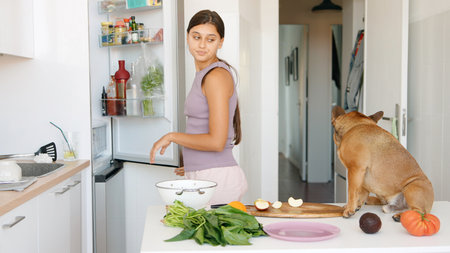 Enjoying a Colorful Cooking Experience in the Kitchen While Being Accompanied by a Playful Dogの写真素材