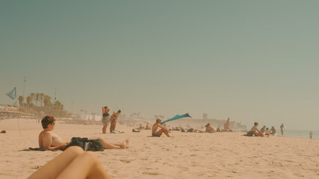 A Beautiful and Relaxing Beach Scene Featuring Sunbathers on Soft, Warm Sand Under the Bright Sun