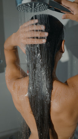 A woman showers elegantly, her long hair flowing as she enjoys a refreshing experience