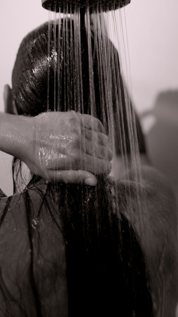A woman showers with water gently flowing over her beautiful hair, embracing serenityの写真素材