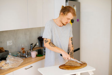 Trimmed for safety, Man cuts sourdough bread amid rustic setting