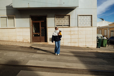 Young woman pausing on urban sidewalk, commuter momentの写真素材