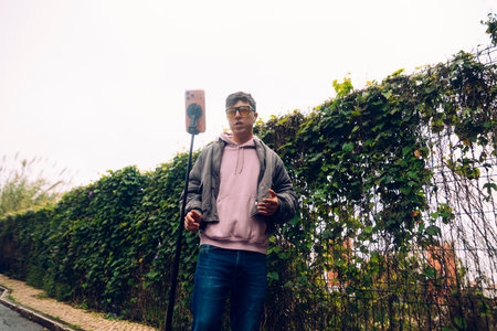 Individual capturing informal audio broadcast amid urban foliage and setup