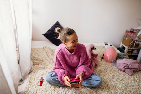 Casual teenage girl gaming calmly on bed with controller in hand