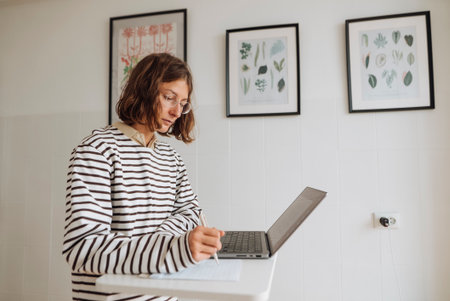 Female working on online store listings with botanical decor nearbyの写真素材