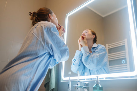Woman applying lipstick at LED mirror - night out makeup prepの写真素材