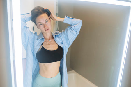Serene morning routine with woman adjusting her hair near bathroom mirror