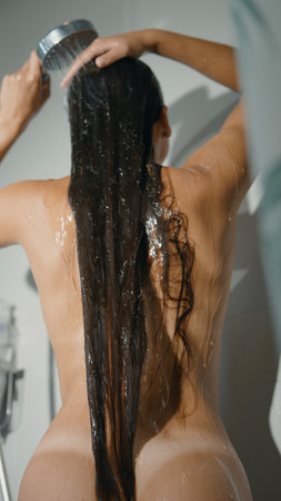 A woman is showering in a stylish and luxurious bathroom setting, enjoying her long hairの写真素材