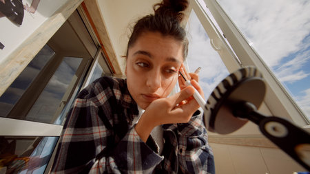 Woman gently applying mascara in serene morning environment