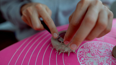 Craftsperson intricately shapes soft clay on silicone mat scene