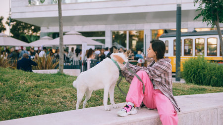 Young woman relaxing with her dog in a city plaza