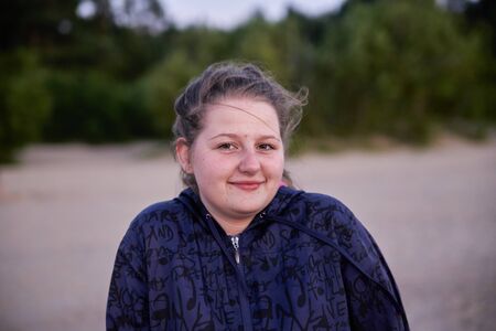 02-08-2017 Riga, Latvia. Portrait of beautiful smiling dark-haired young woman, against summer green park.のeditorial素材