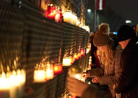 15-10-2019 Riga, Latvia. Woman lighting a candle at wall.