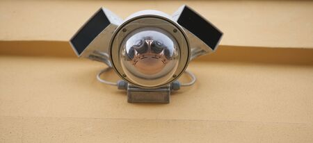 Security video camera on the yellow wall.