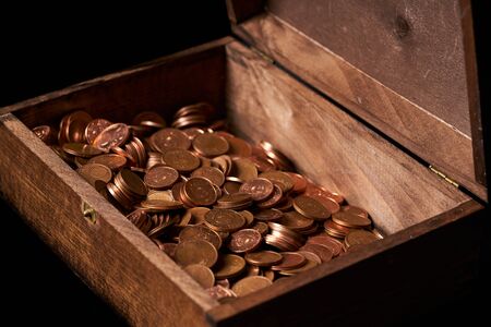 Euro coins in chest on black backgrtound. View from side.