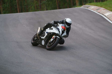 man riding motorcycle in asphalt road. Motorcyclist at black and white sport motorcycle.