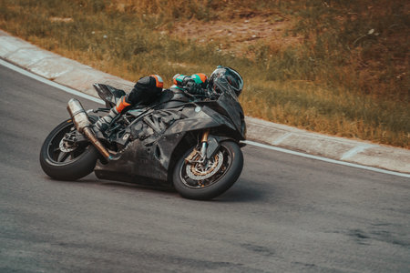 man riding motorcycle in asphalt road. Motorcyclist in black suit at black sport motorcycle.のeditorial素材