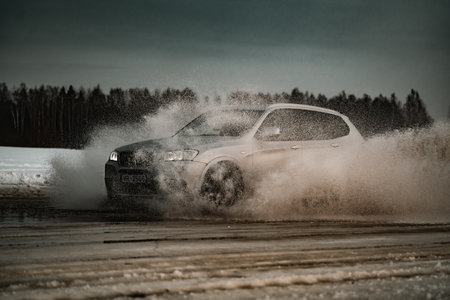 Riga, Latvia 10 February 2021 - bmw rides on water, spray from the car. Front view.のeditorial素材