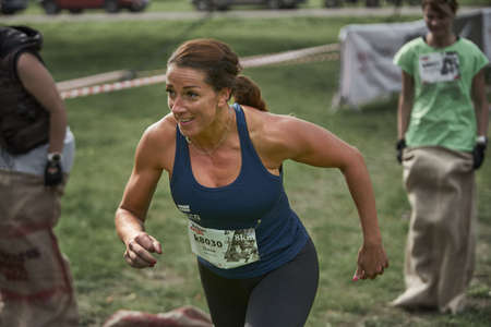 Muscular young woman athlete standing looking down with her hands on hips on grey background. Woman bodybuilder relaxing after exercise.のeditorial素材